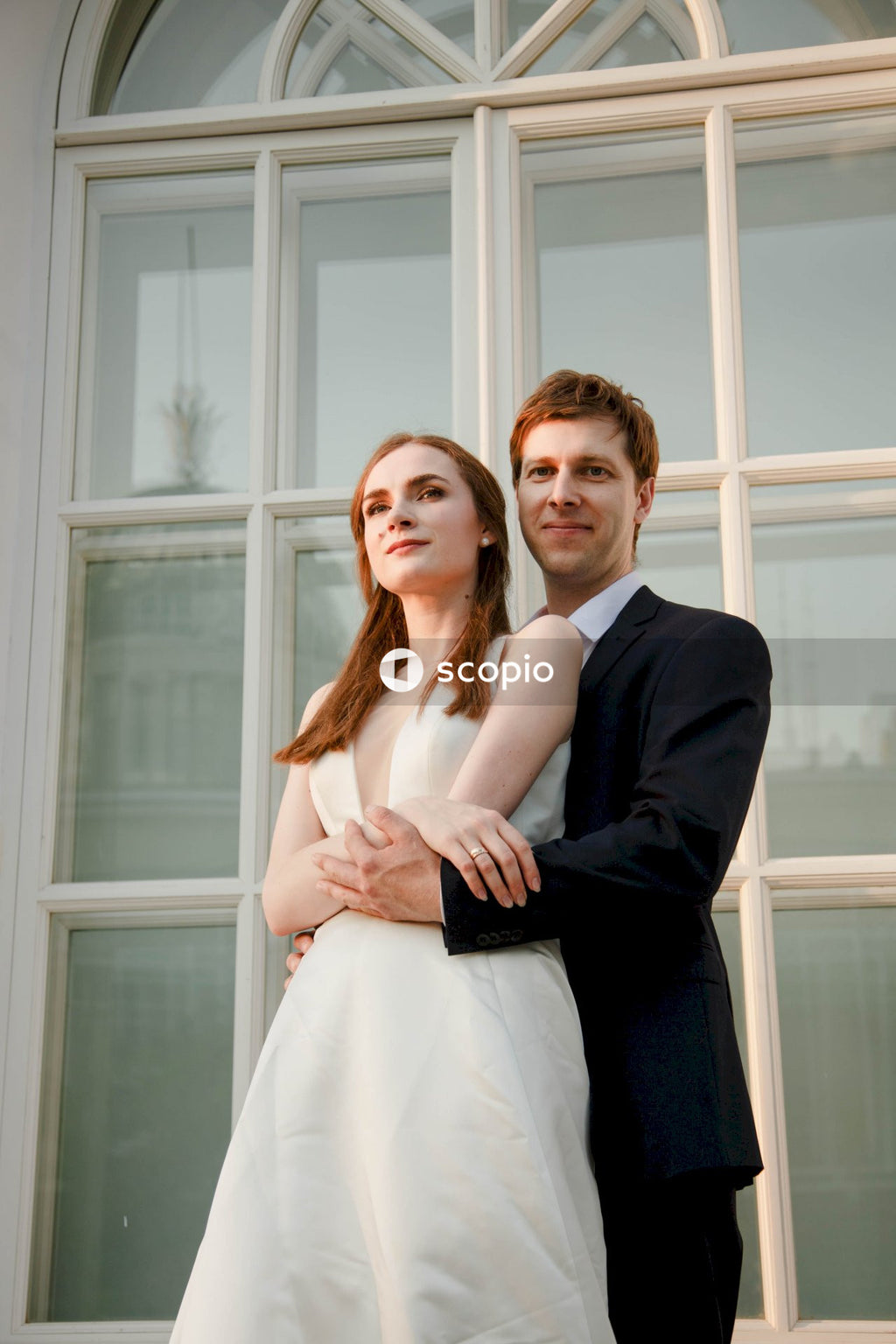 Man in black suit jacket hugging woman in white dress