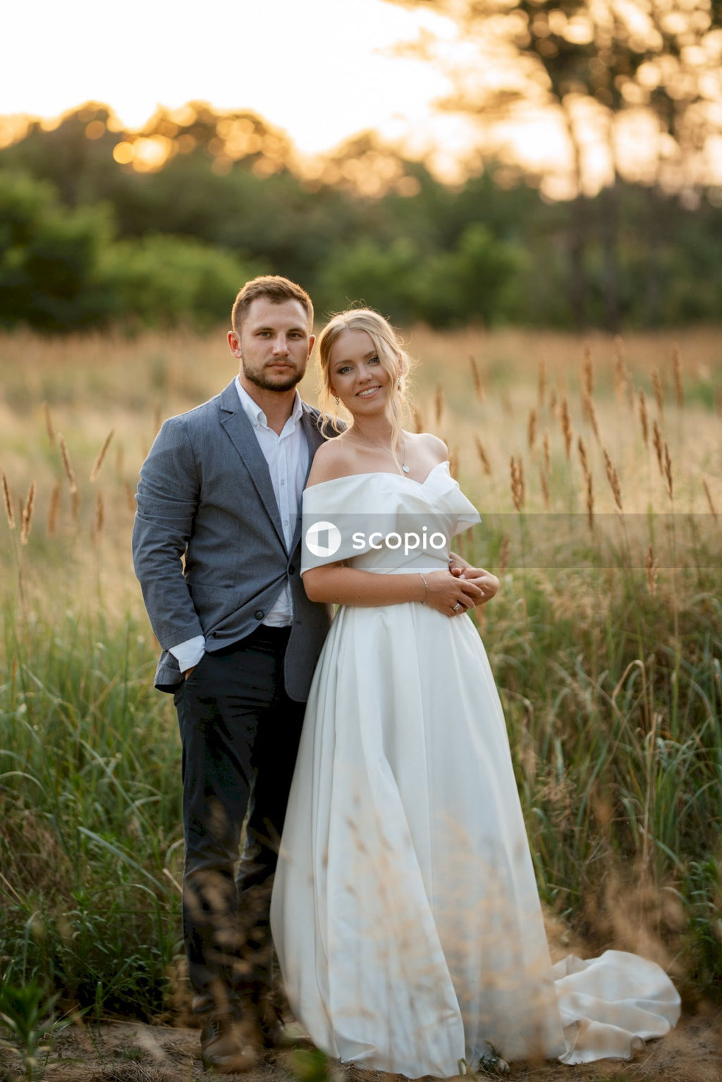 Man in black suit jacket hugging woman in white dress