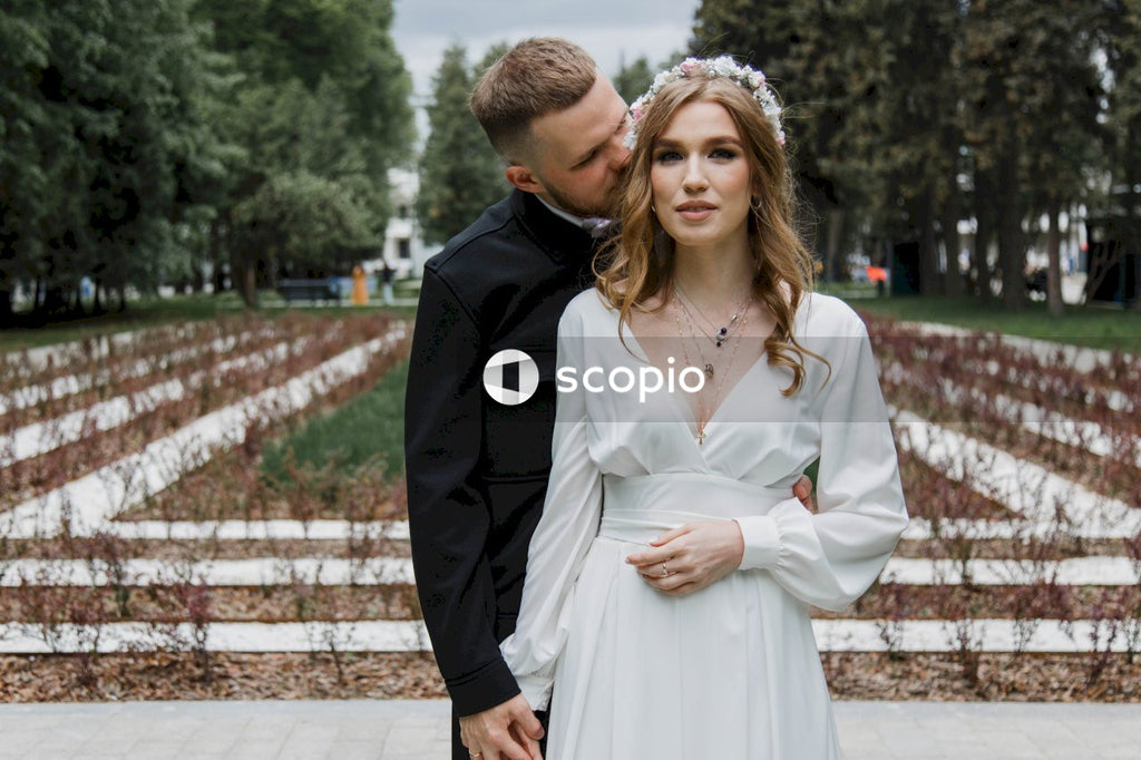 Man in black suit jacket hugging woman in white dress