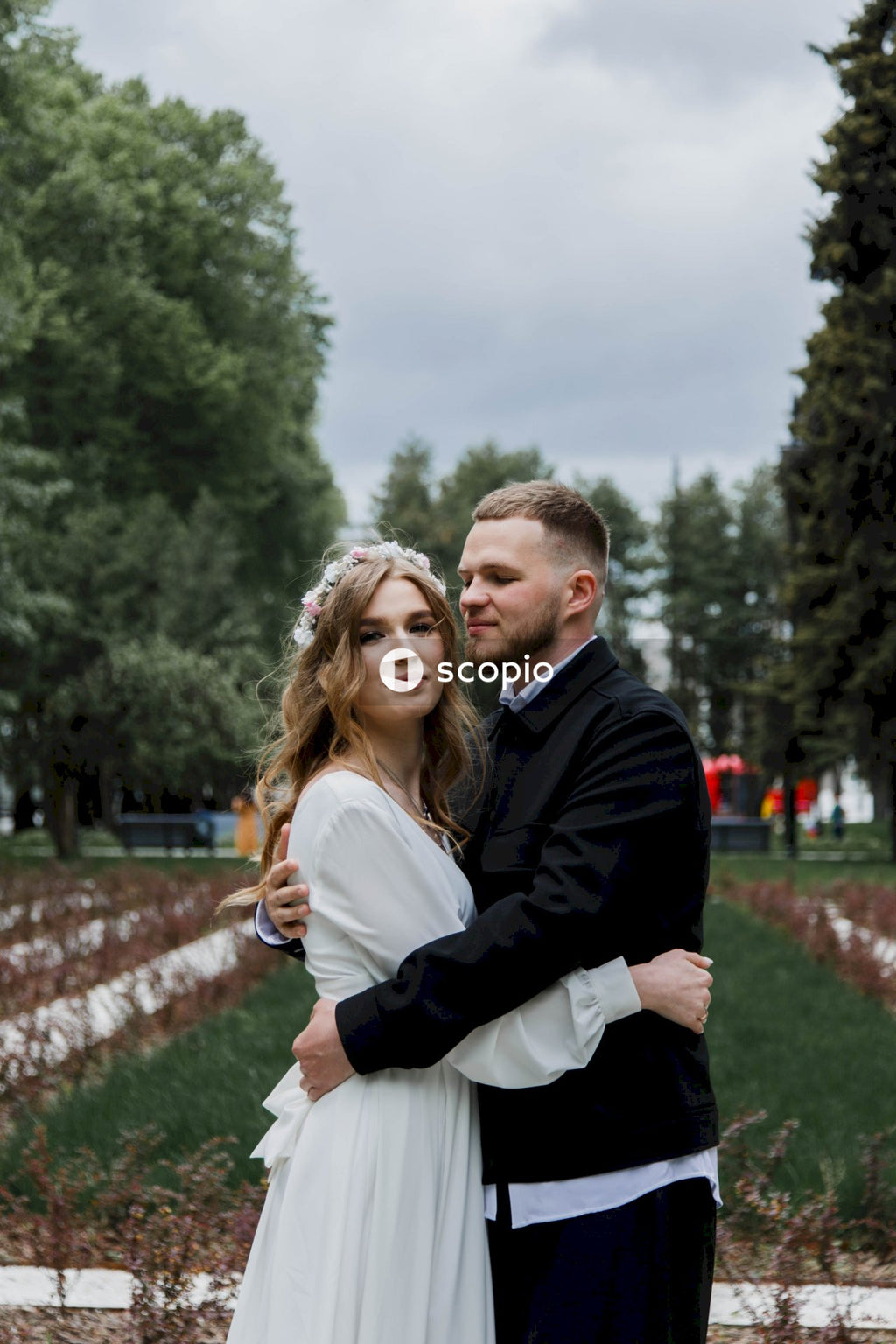 Man in black suit jacket hugging woman in white dress