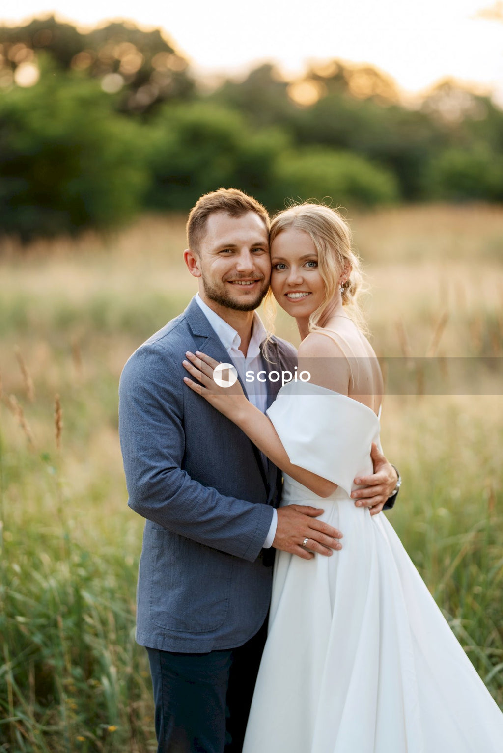 Man in black suit jacket hugging woman in white dress