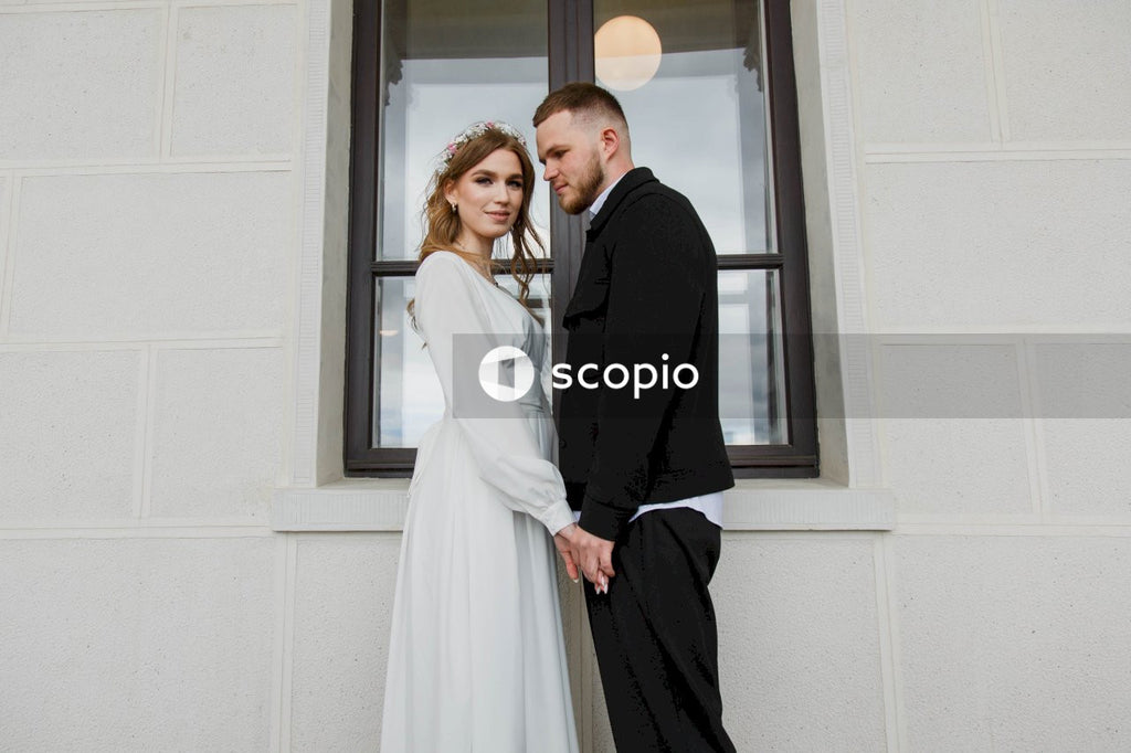 Man in black suit jacket hugging woman in white dress