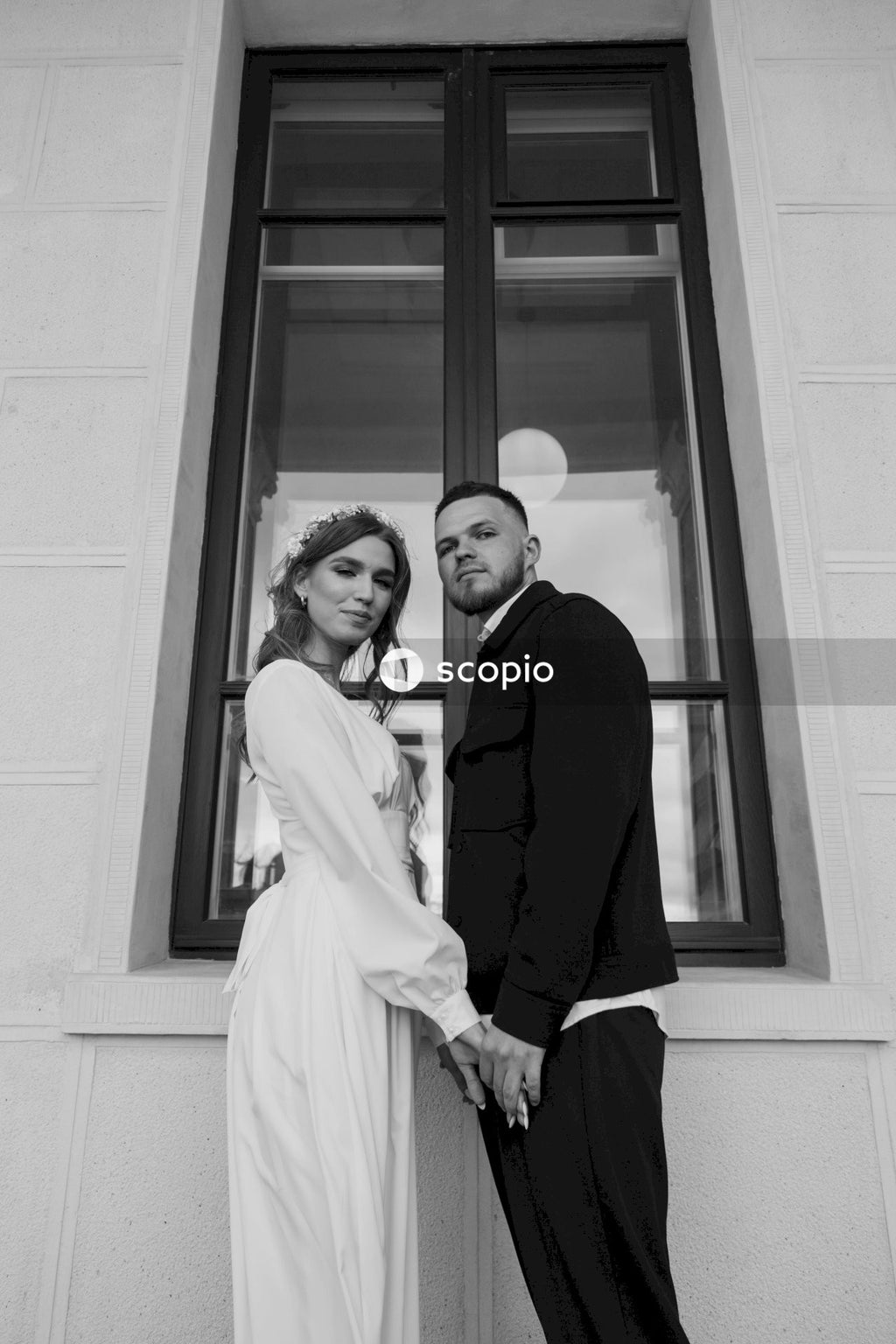 Man in black suit jacket hugging woman in white dress
