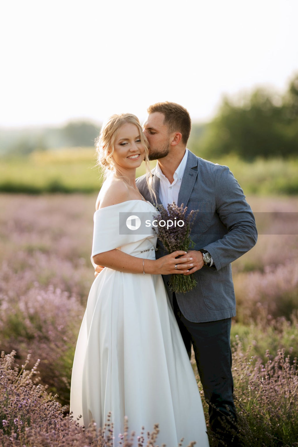 Man in black suit jacket hugging woman in white dress