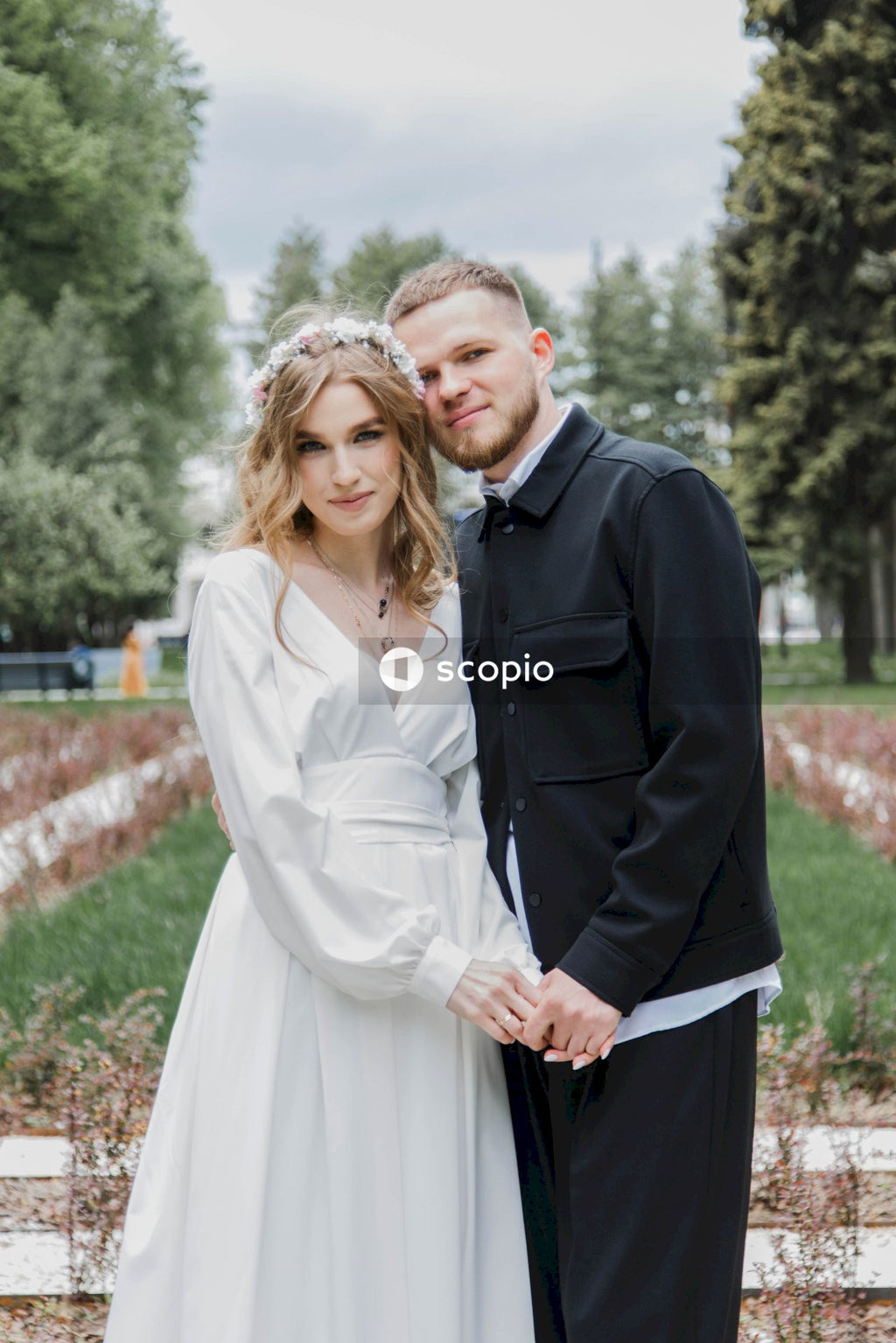 Man in black suit jacket hugging woman in white dress