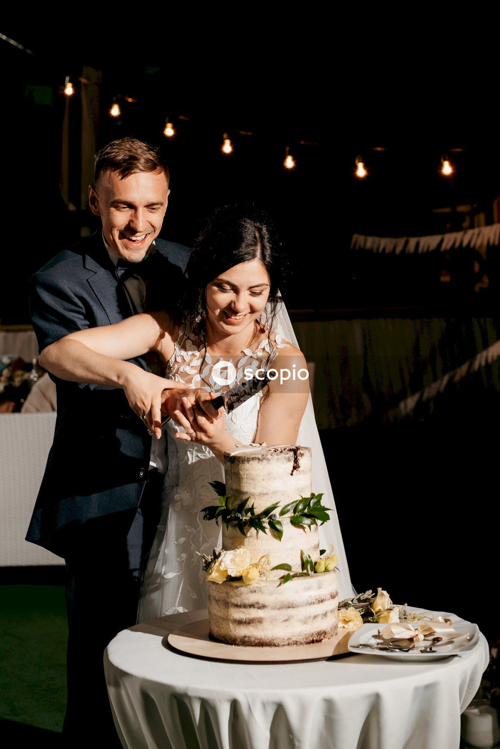 Man in black suit jacket hugging woman in white floral dress