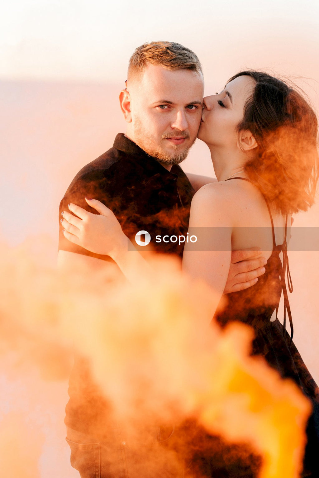 Man in black suit jacket hugging woman in white tank top