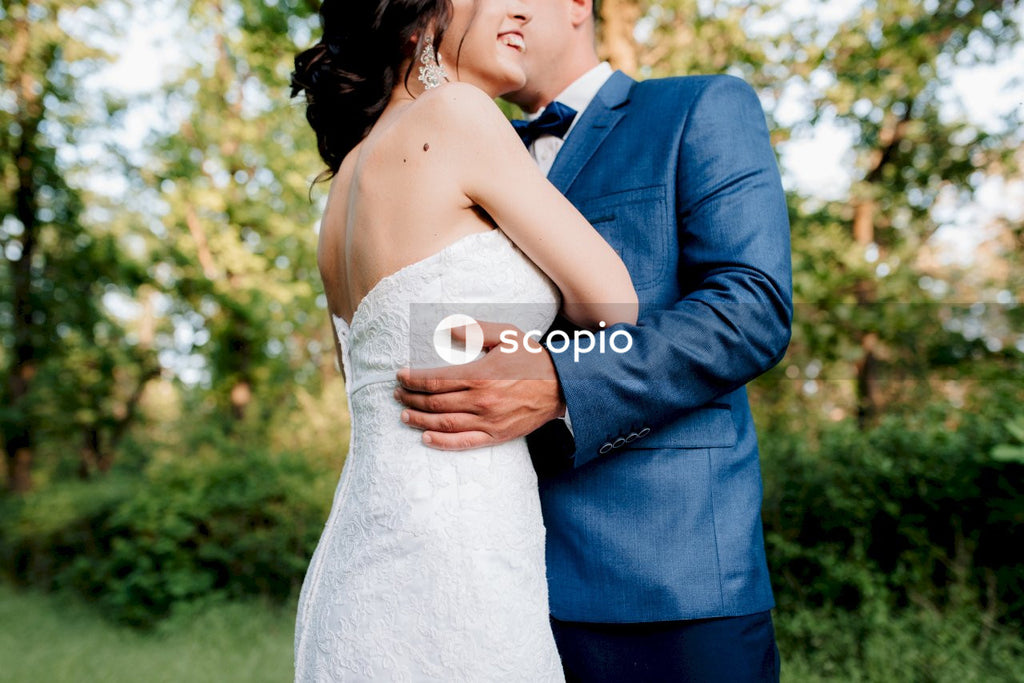 Man in black suit jacket hugging woman in white tube dress