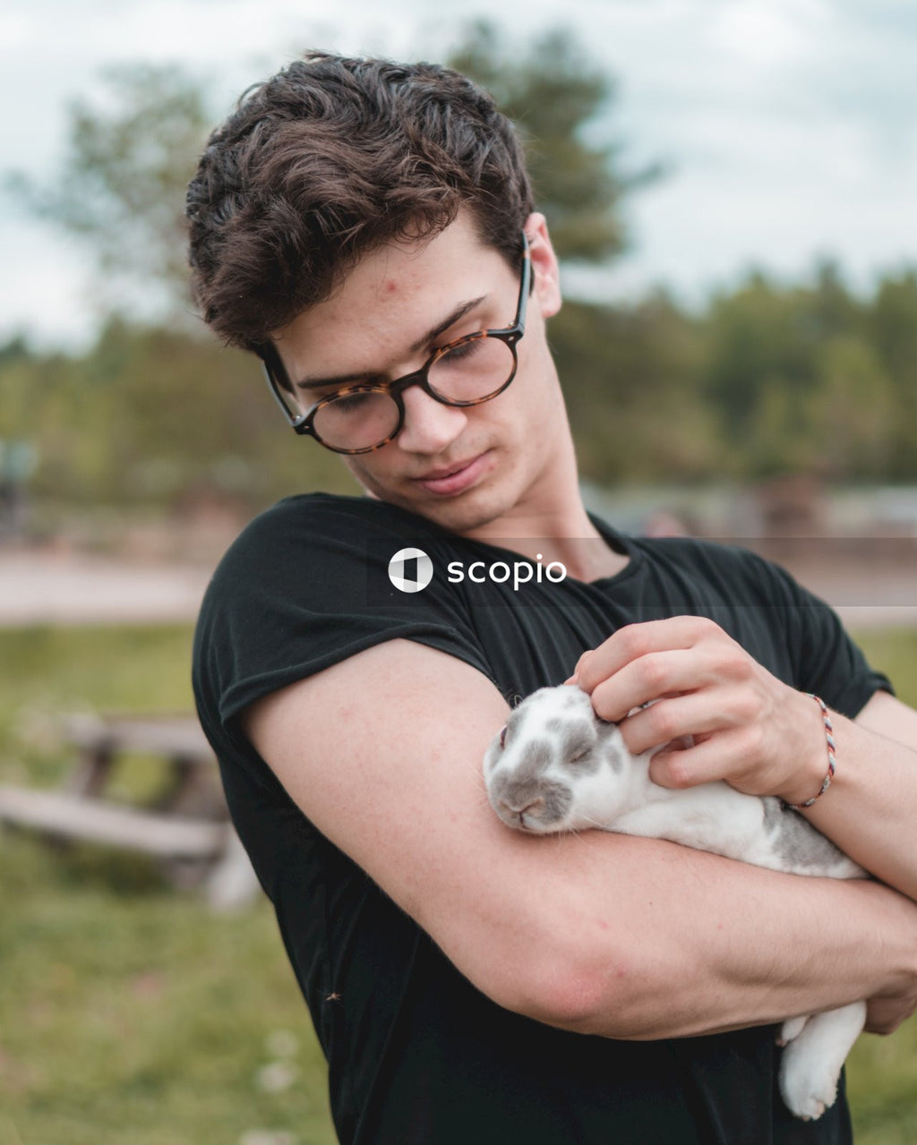 Man in black t-shirt hugging white and brown short coated puppy