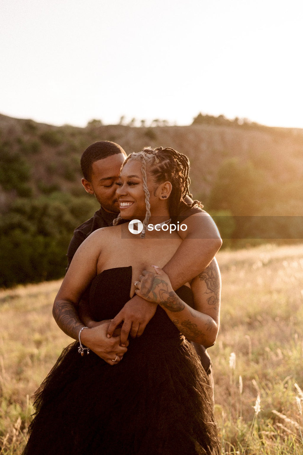 Man in black tank top kissing woman in brown dress