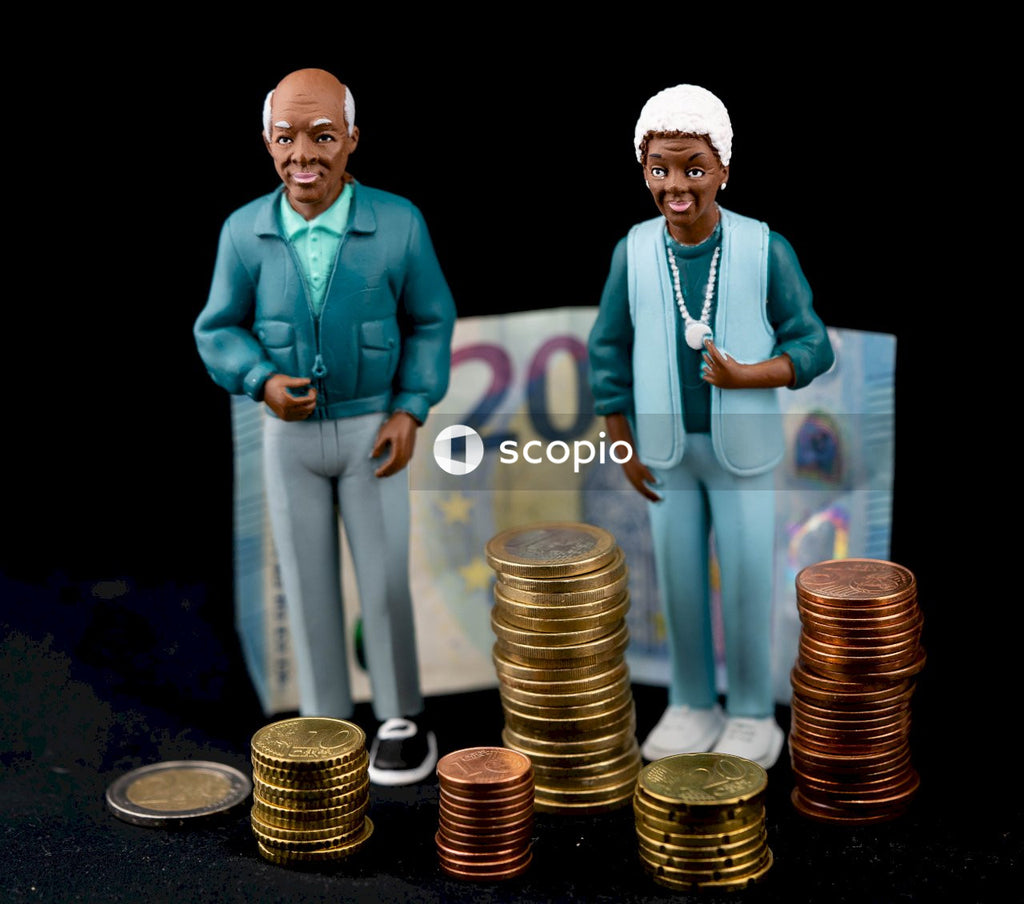 Man in blue blazer and white pants standing beside gold coins