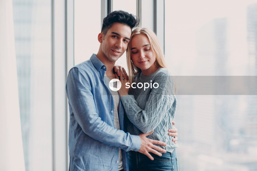 Man in blue dress shirt hugging woman in blue denim jacket