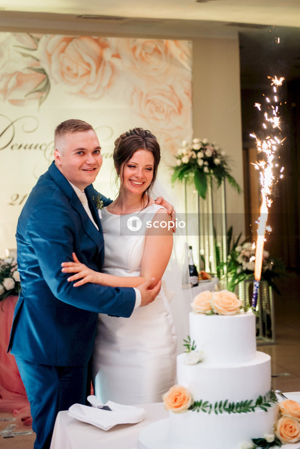 Man in blue suit jacket hugging woman in white dress