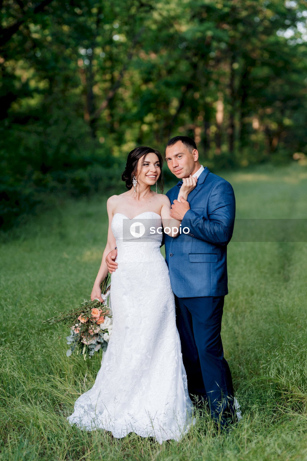 Man in blue suit jacket hugging woman in white wedding dress