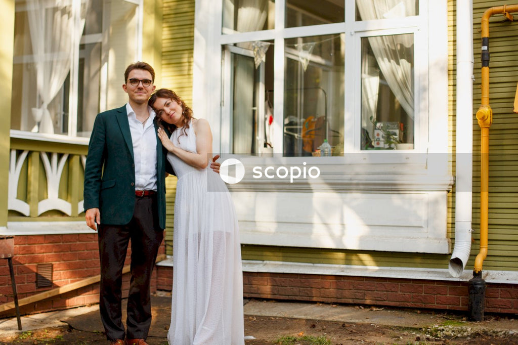Man in blue suit jacket standing beside woman in white dress