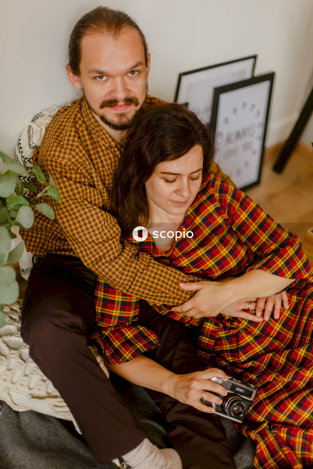 Man in brown and black plaid dress shirt hugging woman in brown long sleeve shirt