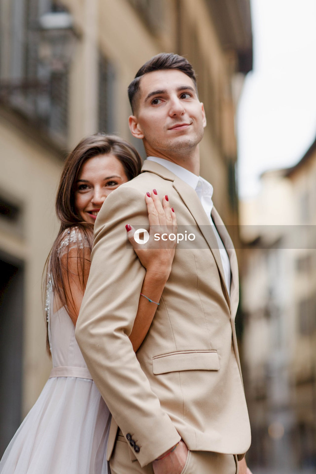 Man in brown coat hugging woman in white coat