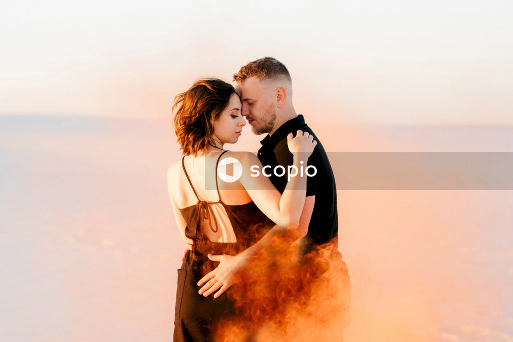 Man in brown coat hugging woman in white tank top