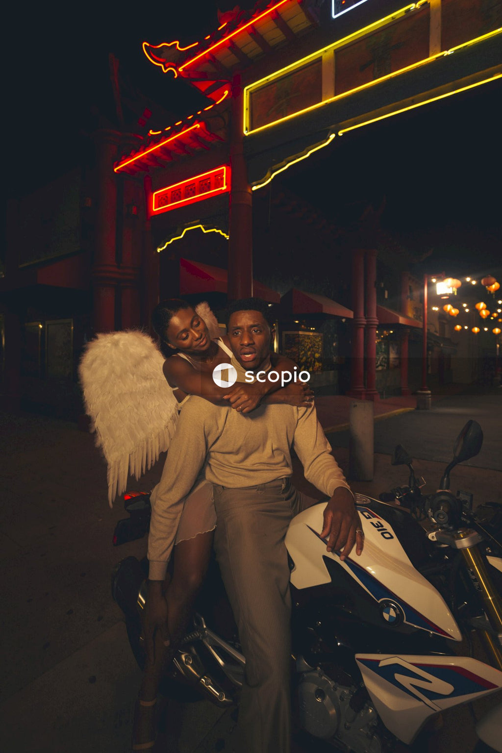 Man in brown jacket hugging woman in white fur coat