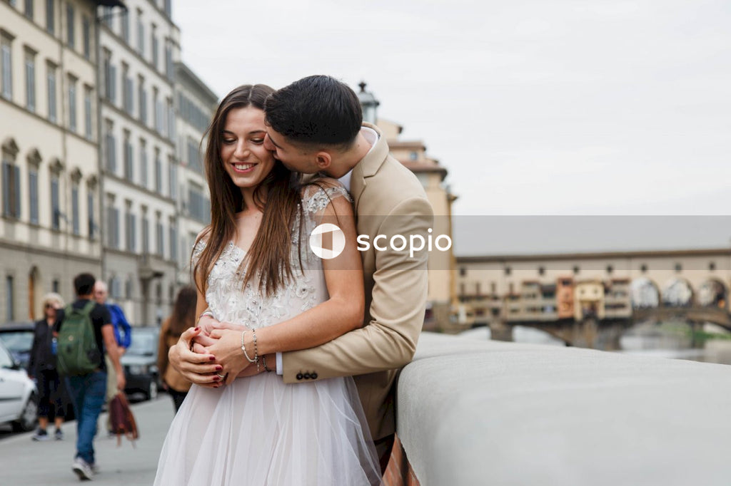 Man in brown suit jacket hugging woman in white dress