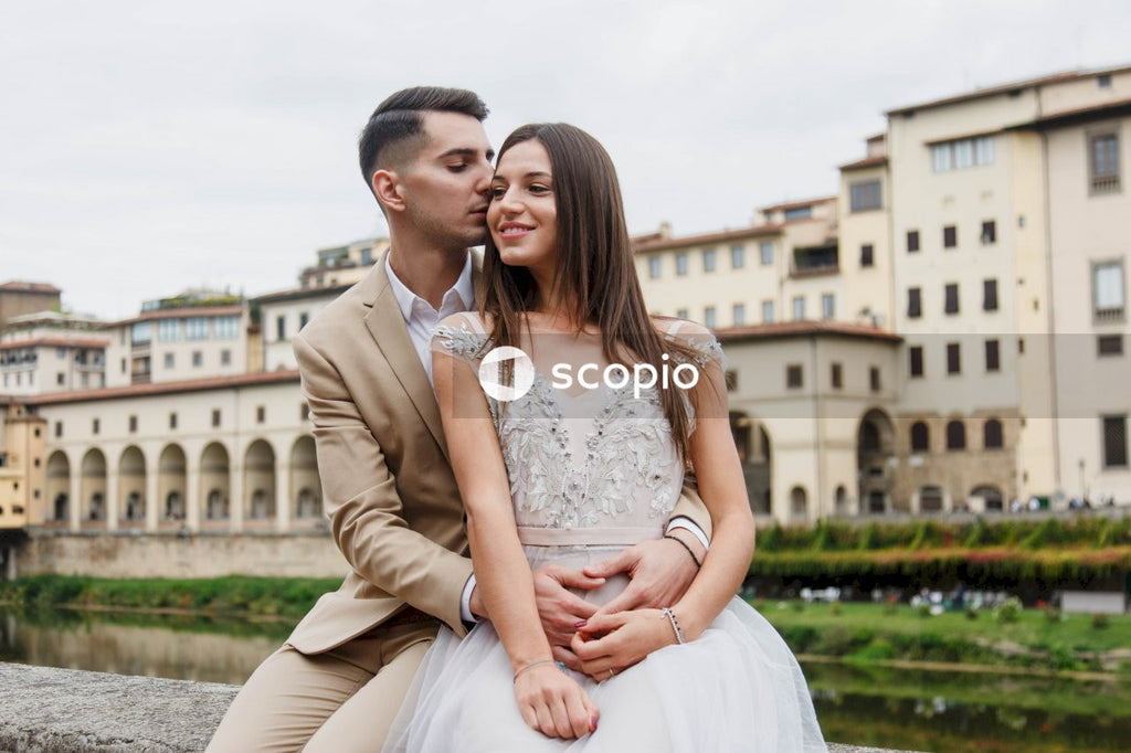Man in brown suit jacket hugging woman in white dress