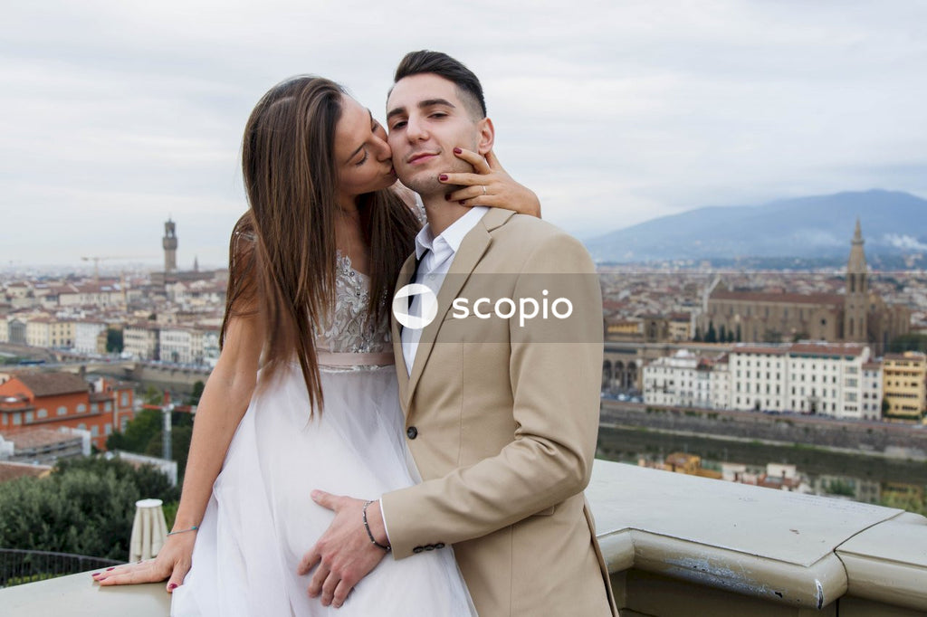 Man in brown suit jacket hugging woman in white dress