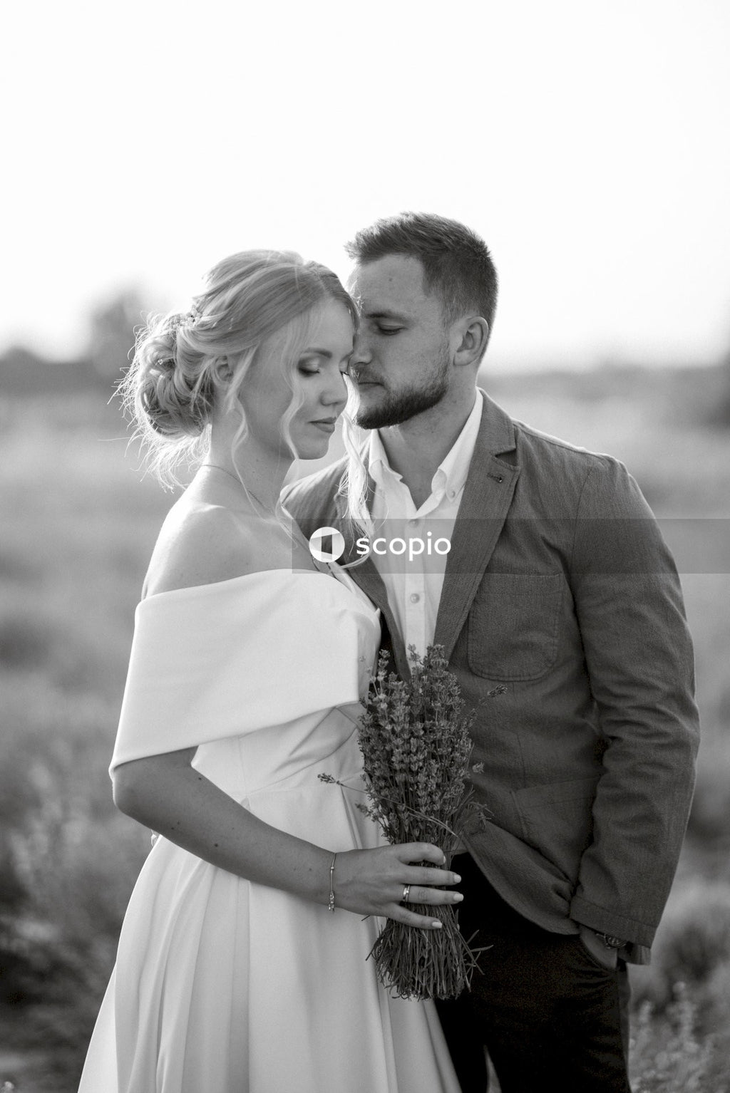 Man in brown suit jacket hugging woman in white dress