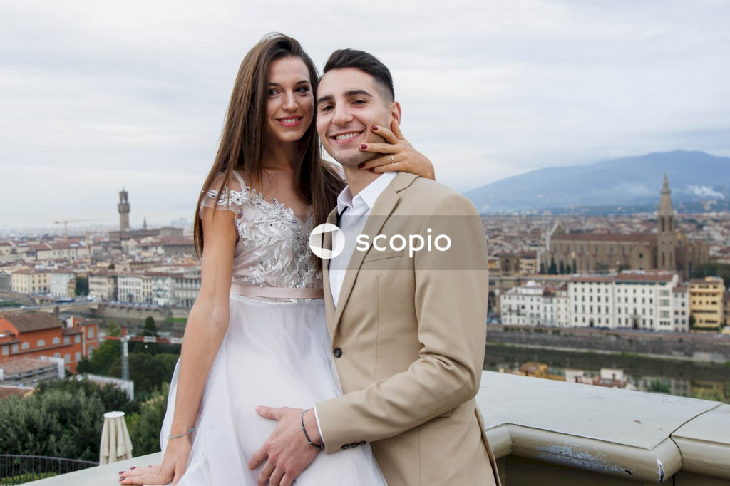 Man in brown suit jacket hugging woman in white dress