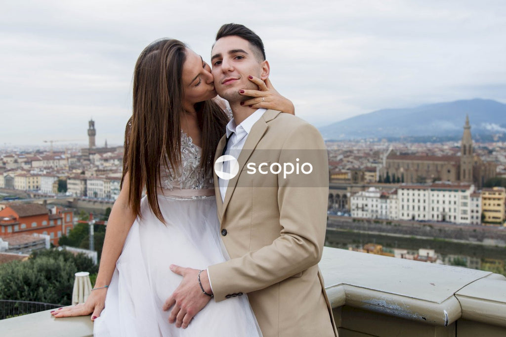 Man in brown suit jacket hugging woman in white dress