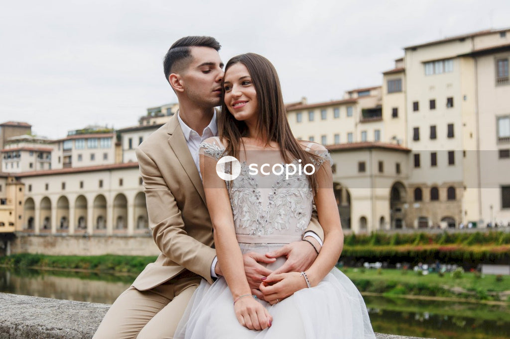 Man in brown suit jacket hugging woman in white dress