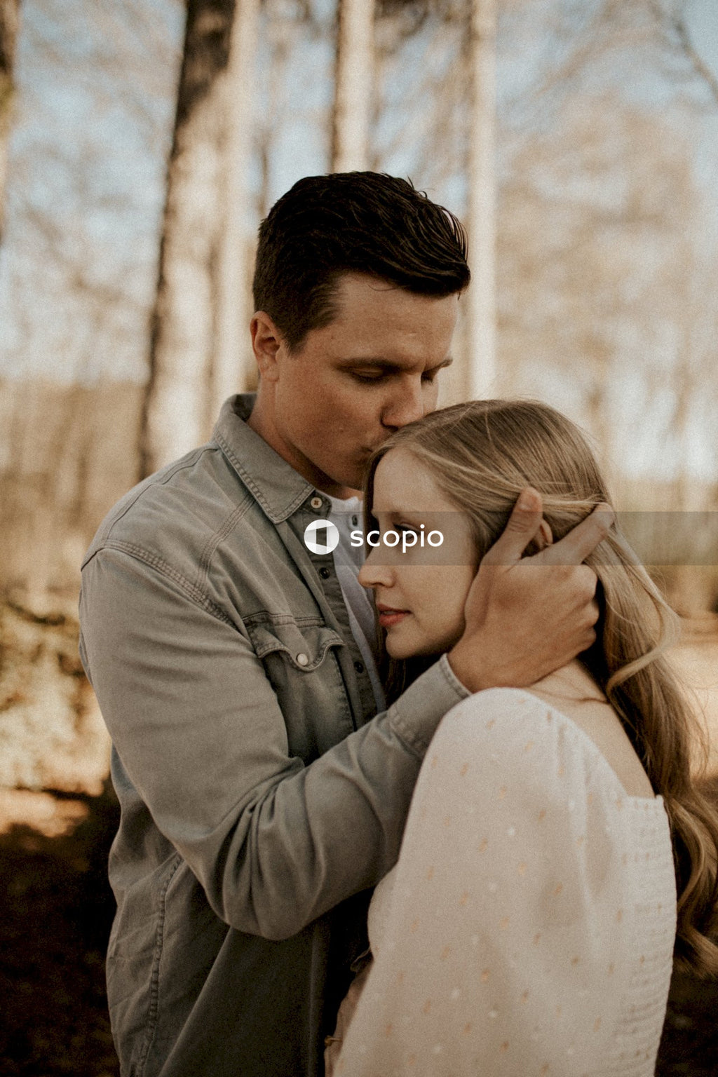 Man in gray dress shirt hugging woman in white dress