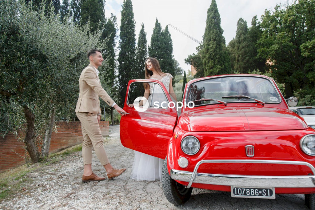 Young married couple doing a photoshoot near small red car