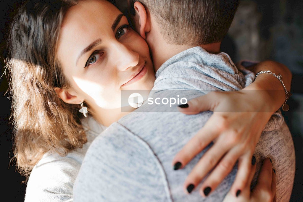 Man in gray shirt hugging woman in white shirt