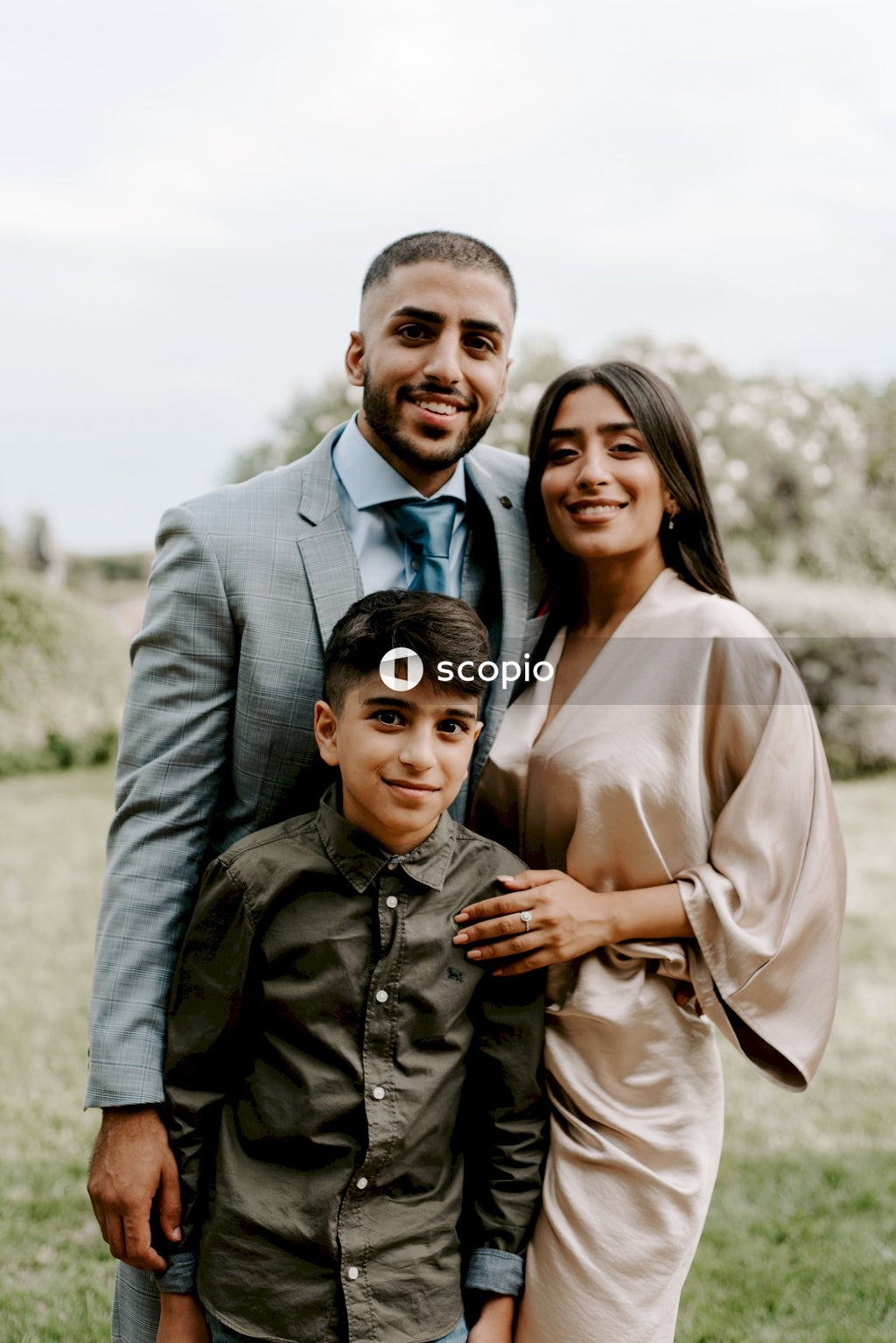 Man in gray suit jacket hugging woman in beige dress