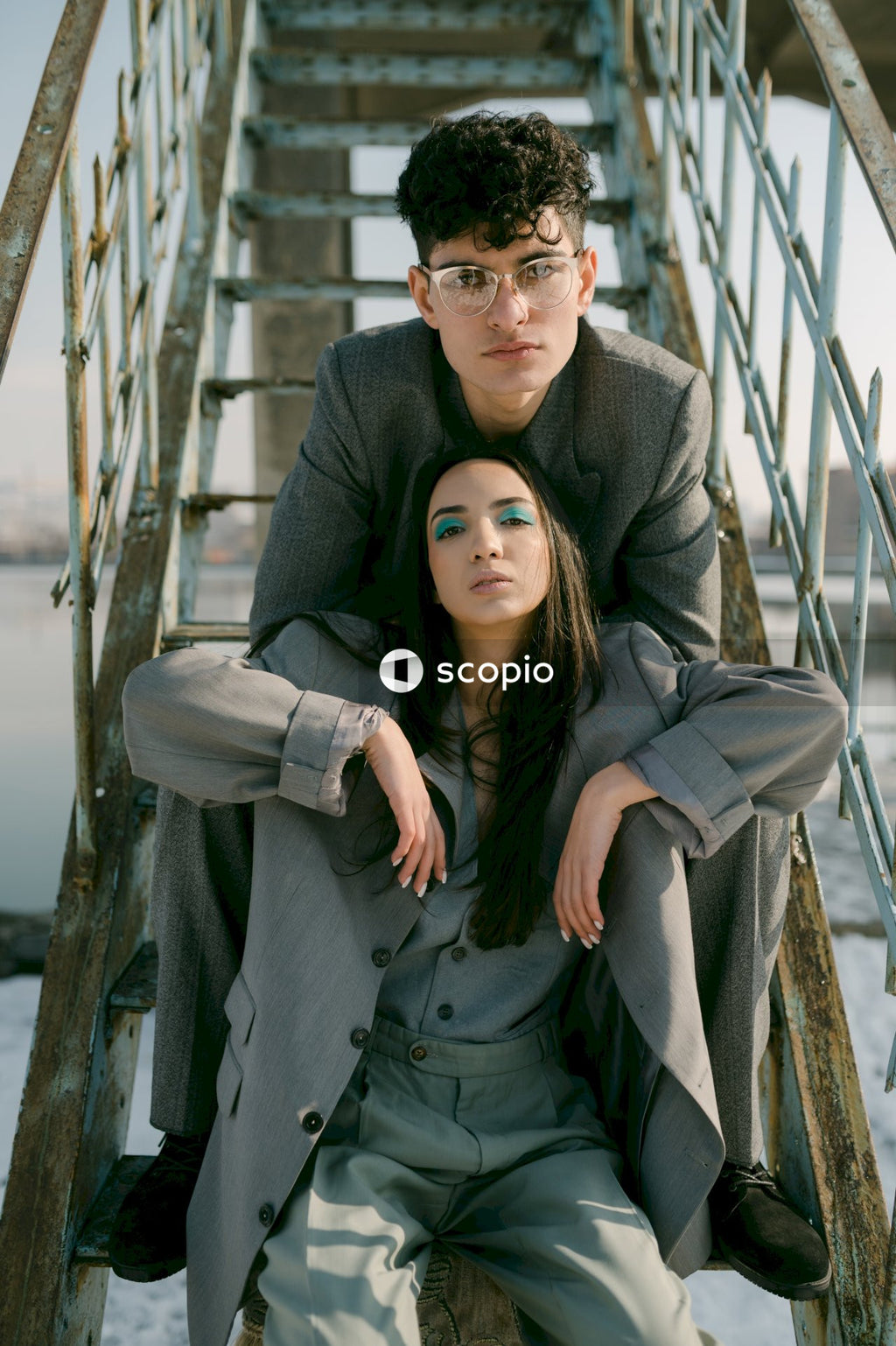 Man in gray suit jacket hugging woman in gray coat