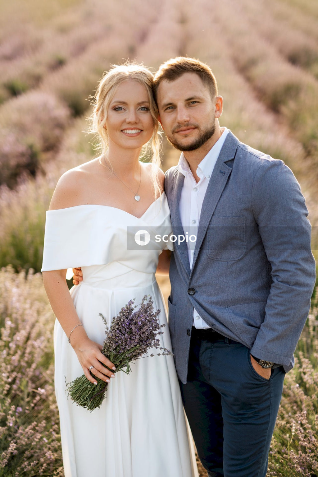 Man in gray suit jacket hugging woman in white dress