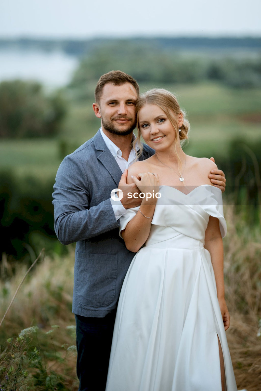 Man in gray suit jacket hugging woman in white dress
