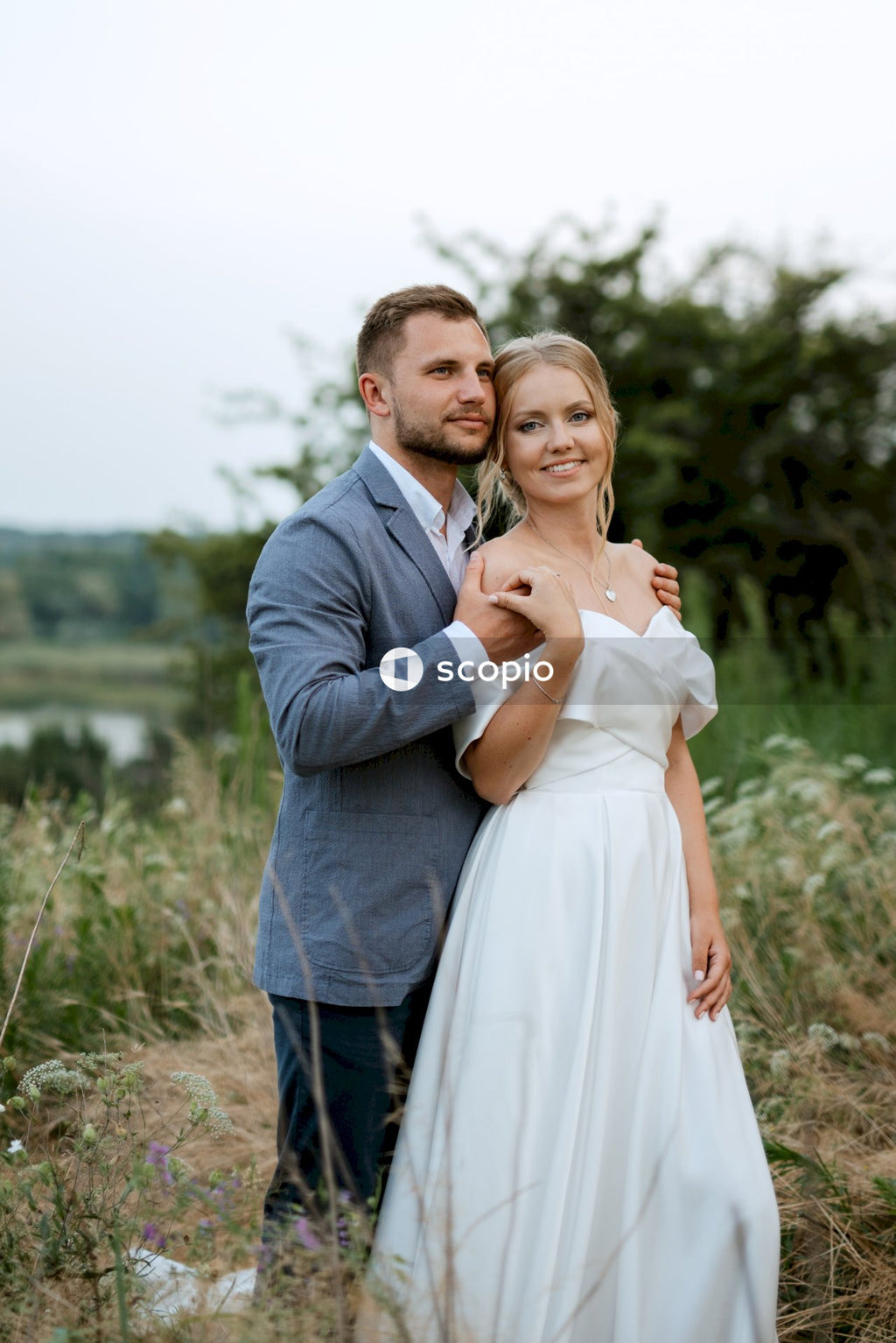 Man in gray suit jacket hugging woman in white dress