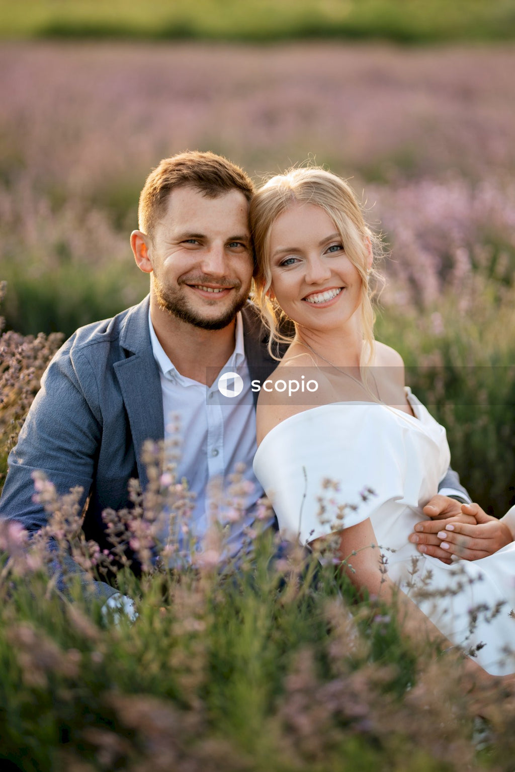 Man in gray suit jacket hugging woman in white dress