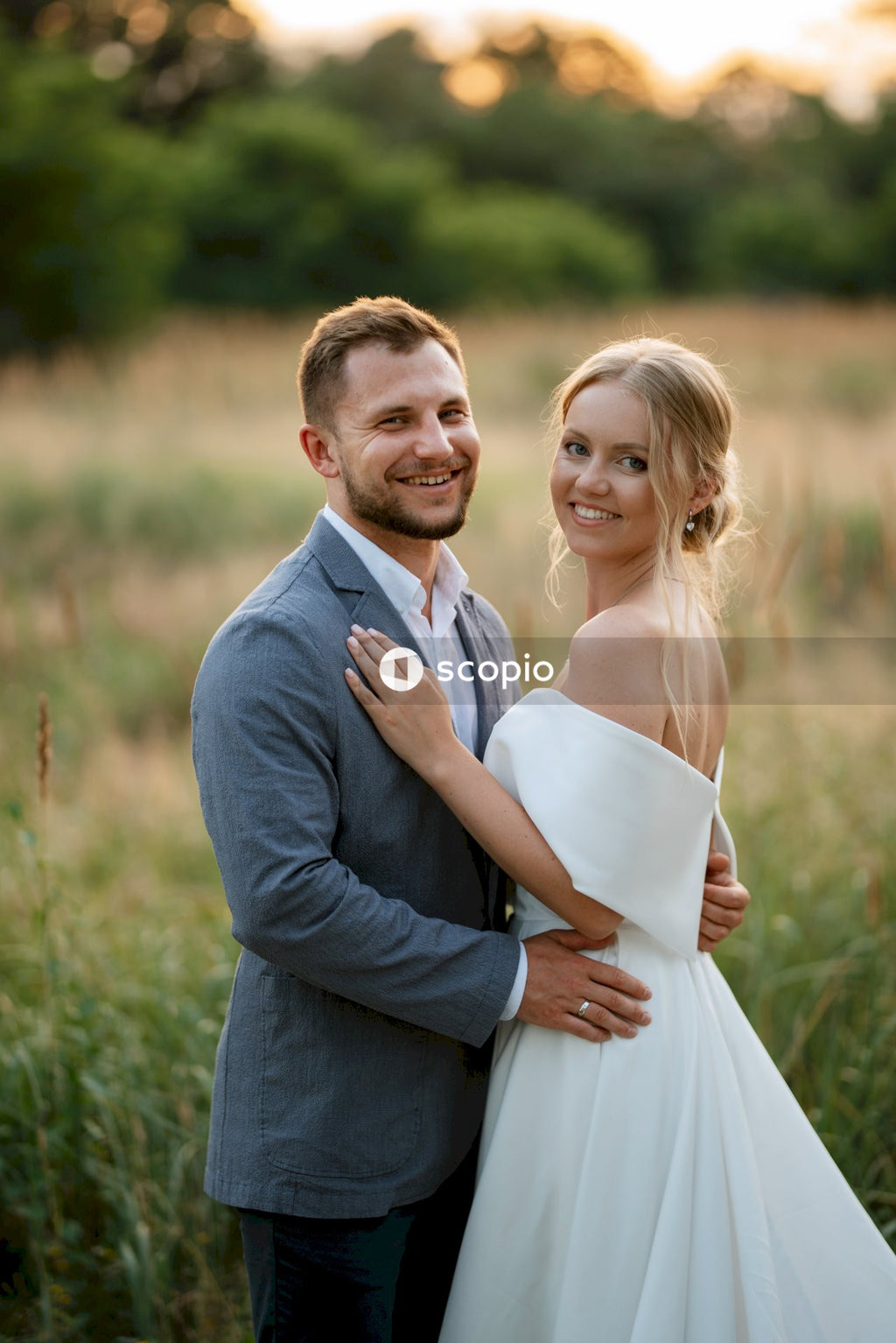 Man in gray suit jacket hugging woman in white dress
