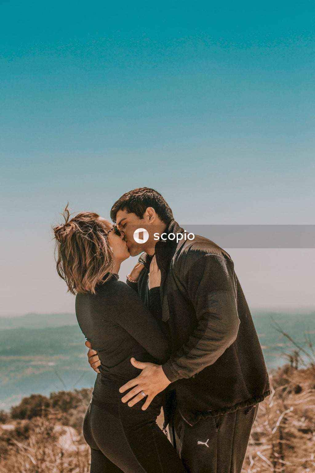 Man in gray suit jacket kissing woman in brown coat