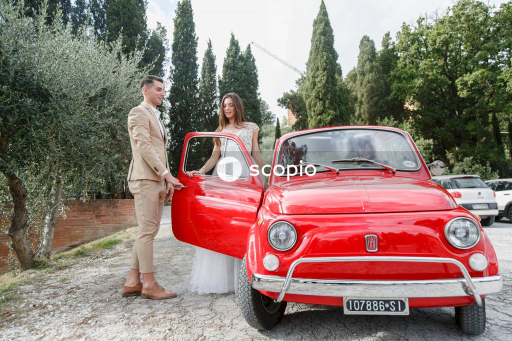 Young married couple doing a photoshoot near small red car