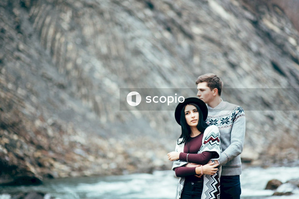 Man in gray sweater hugging woman in black and white long sleeve shirt