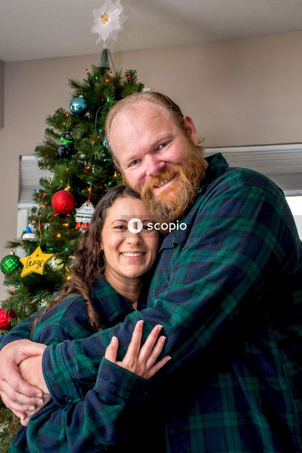 Man in green and black plaid dress shirt hugging woman in green and black plaid long