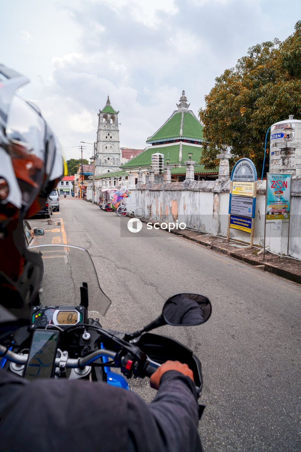Man in orange helmet riding motorcycle on road