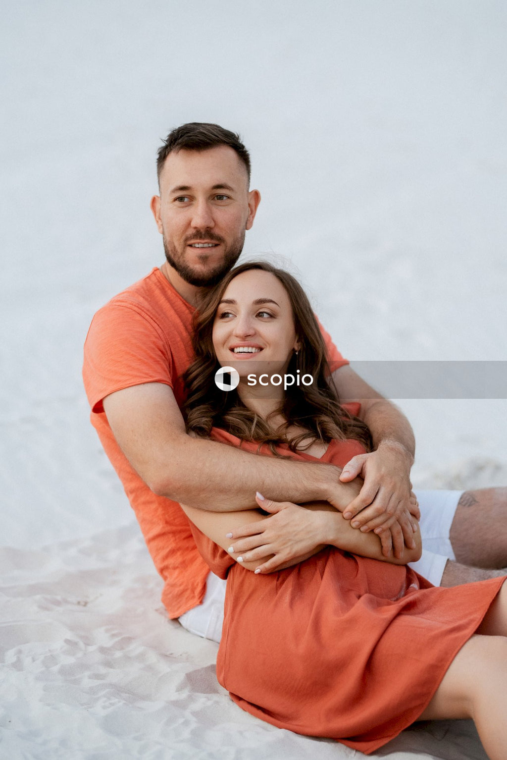 Man in orange t-shirt hugging woman in white t-shirt