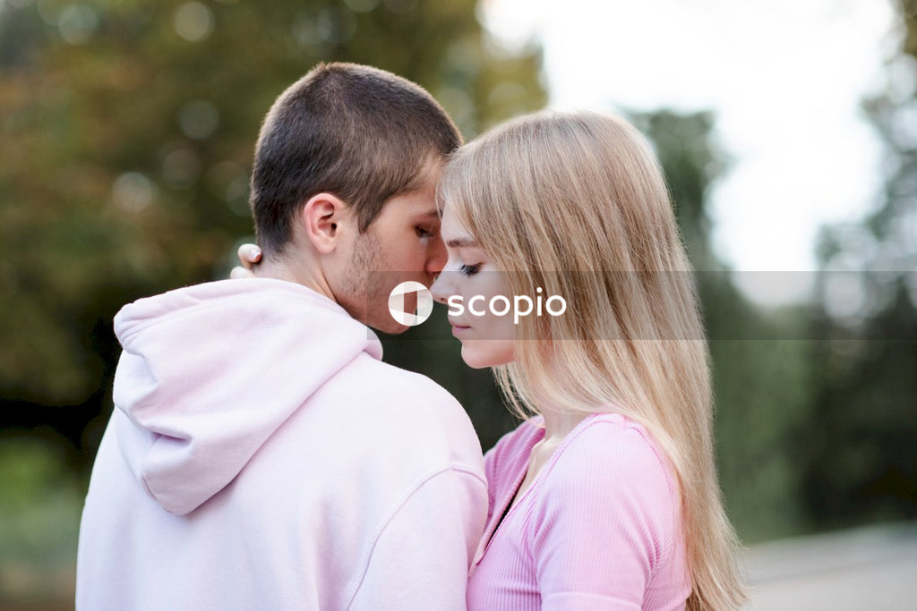 Man in pink dress shirt kissing woman in pink shirt
