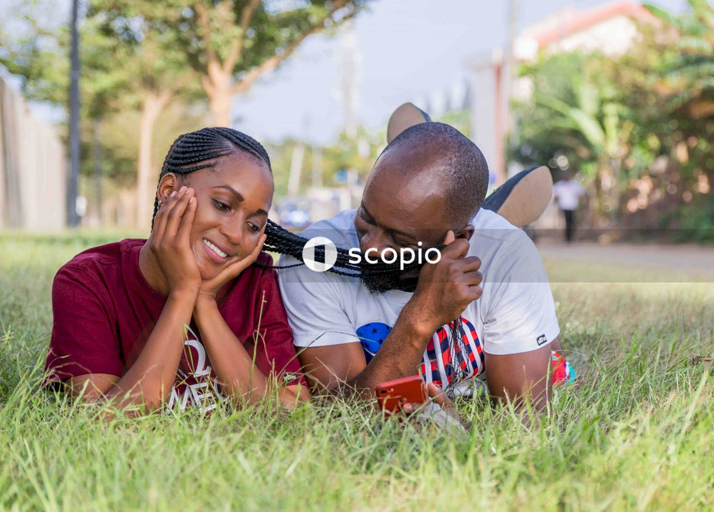 Man and woman lying on green grass having a romantic moment