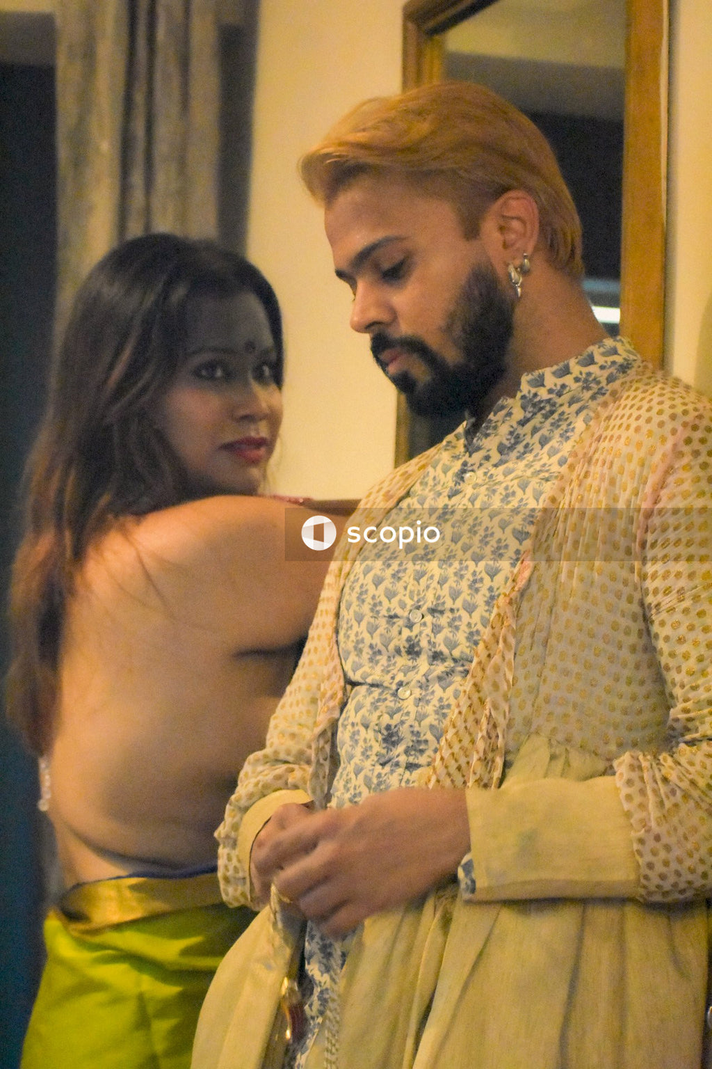 Woman in yellow sari standing beside a man indoor