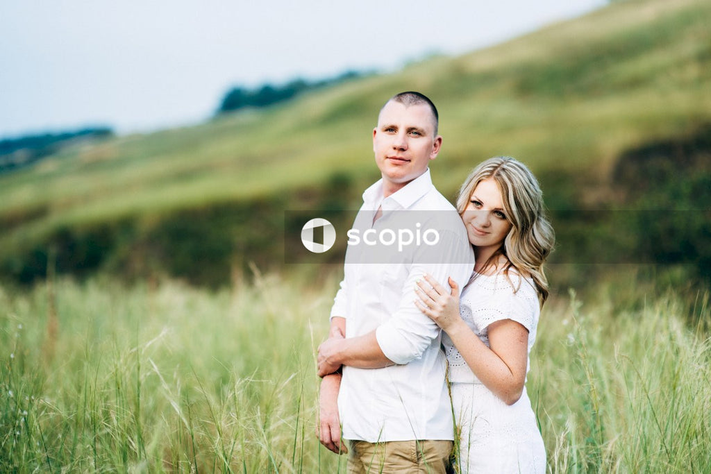 Man in white button up shirt hugging woman in white dress